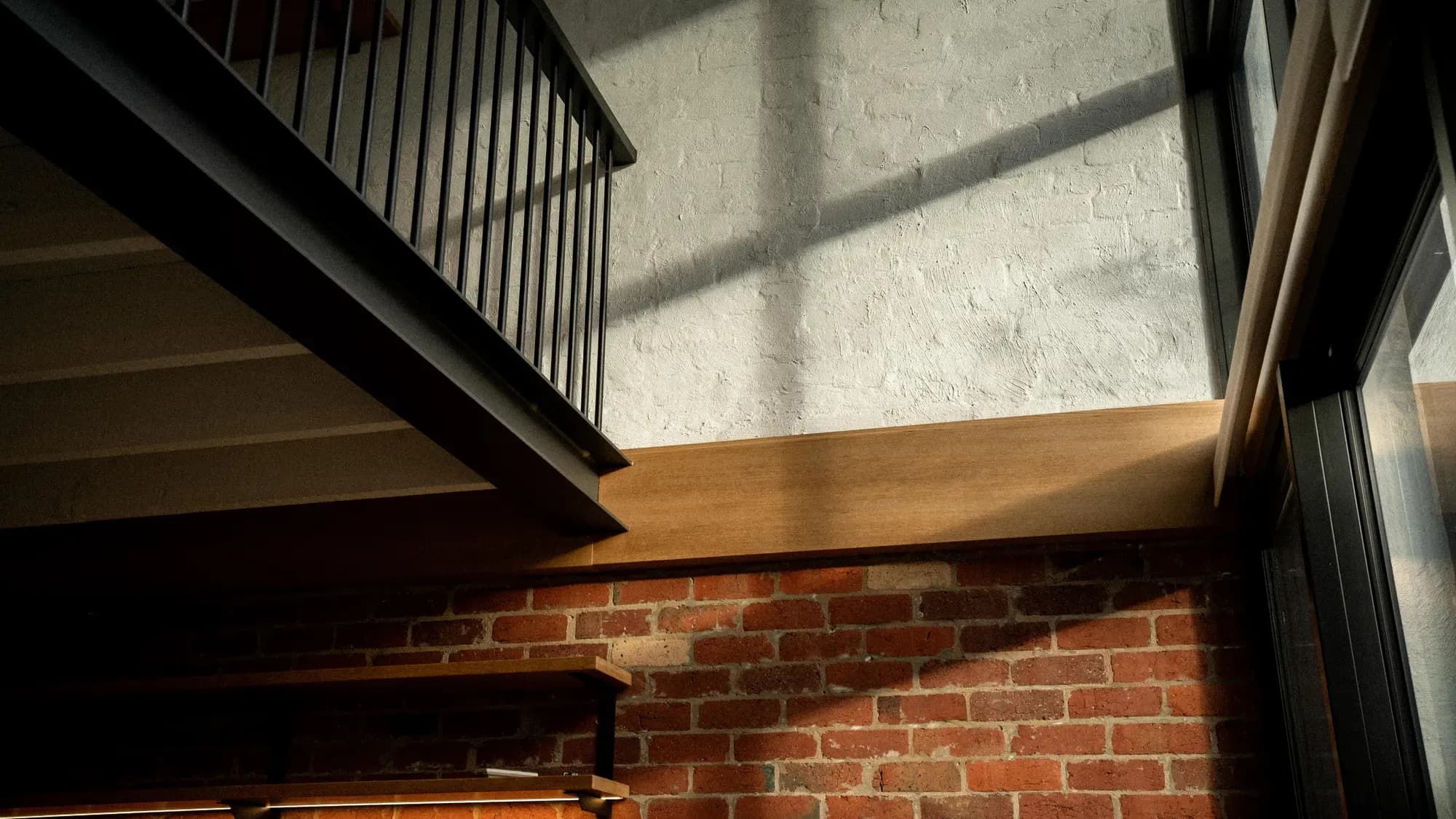 Timber and exposed brick beneath the steel balustrade of the upper level