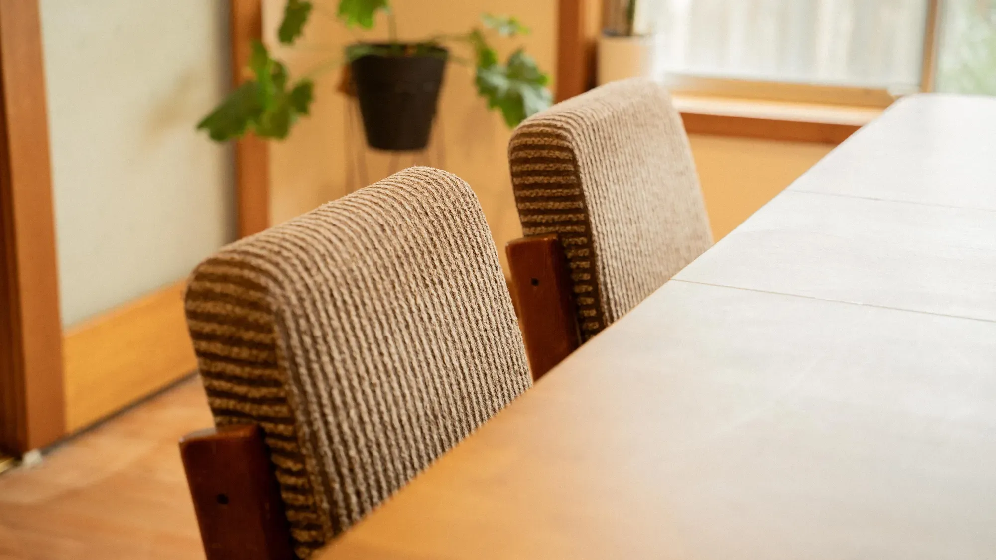 Dining chairs drawn up to the table beneath the window