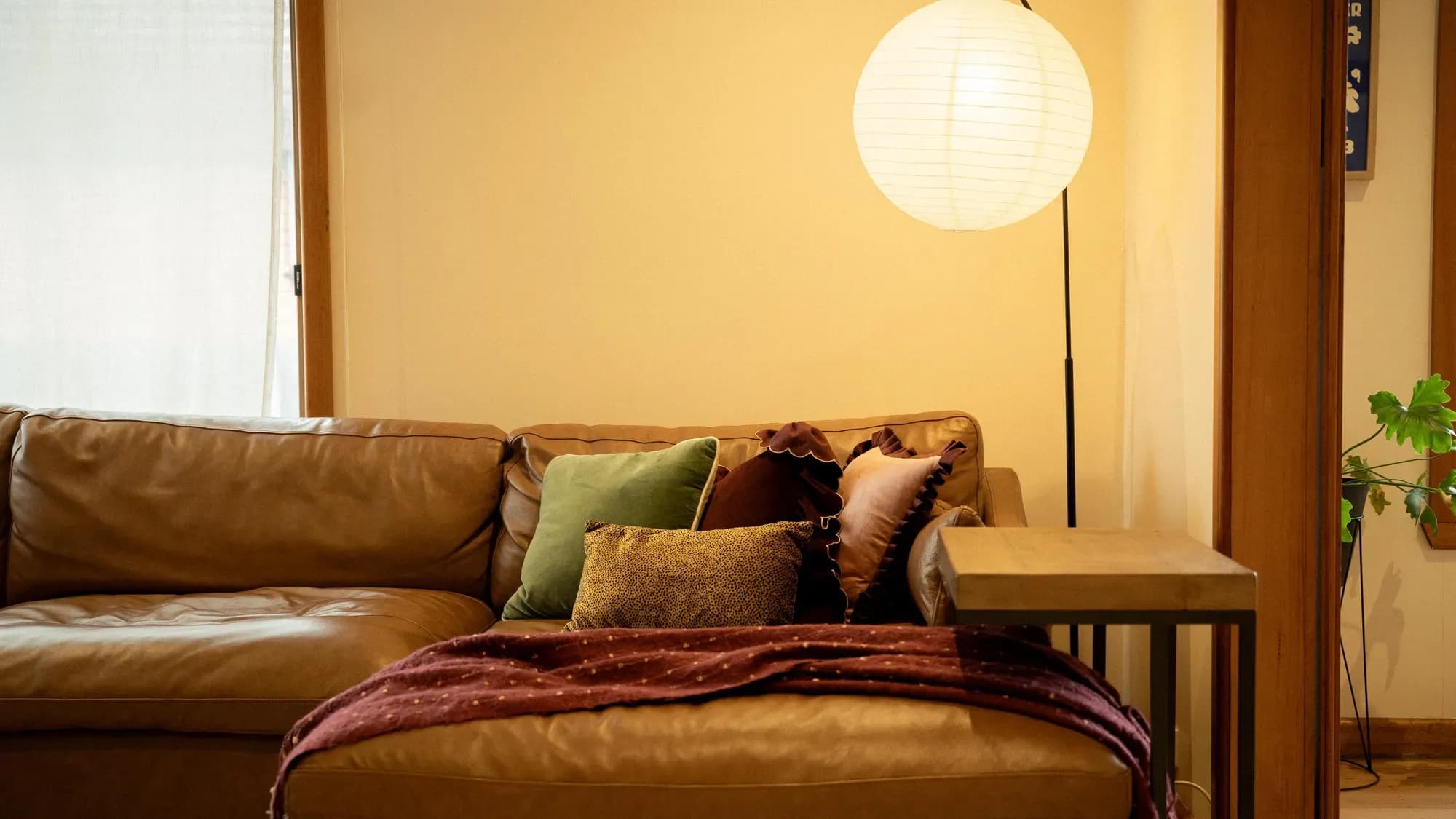 A leather sofa under a paper lantern, a throw across one arm