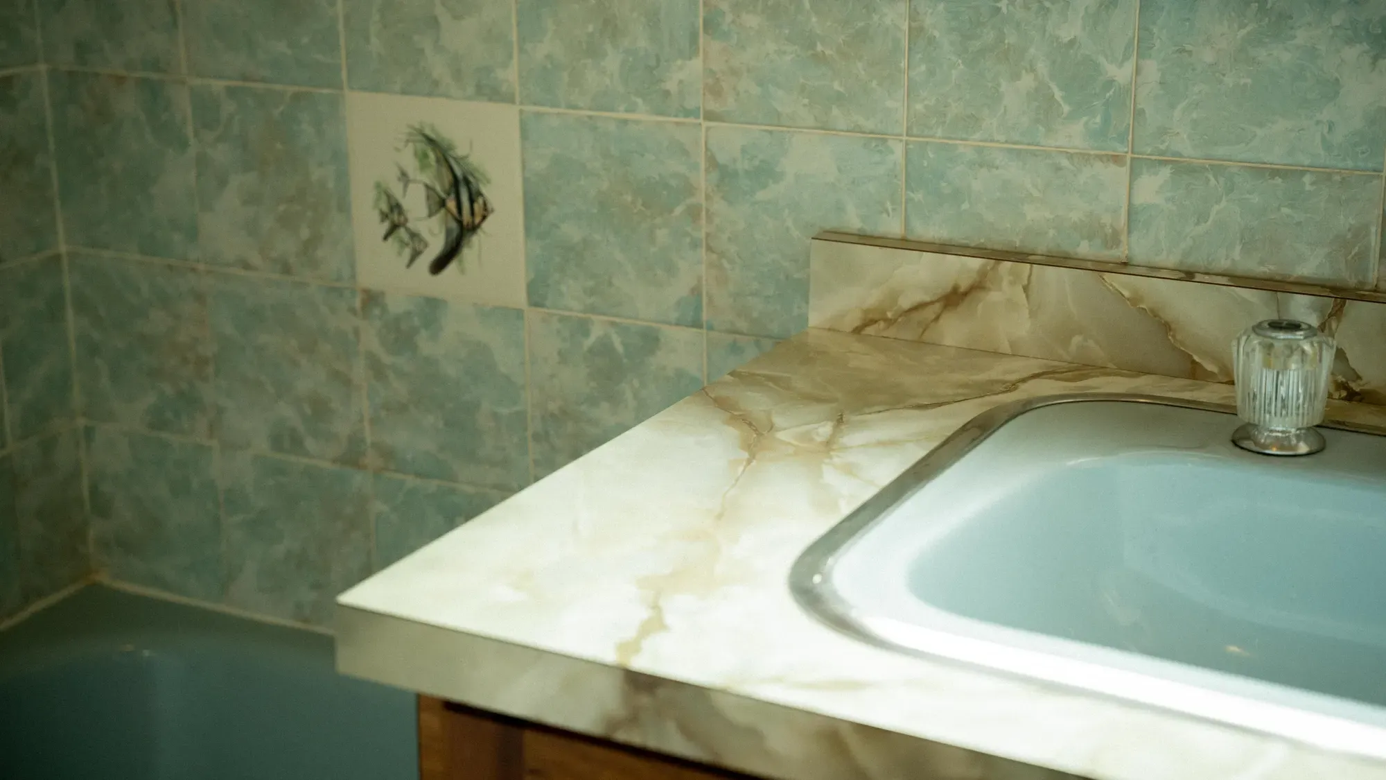 A tiled bathroom with a bath set into a stone surround