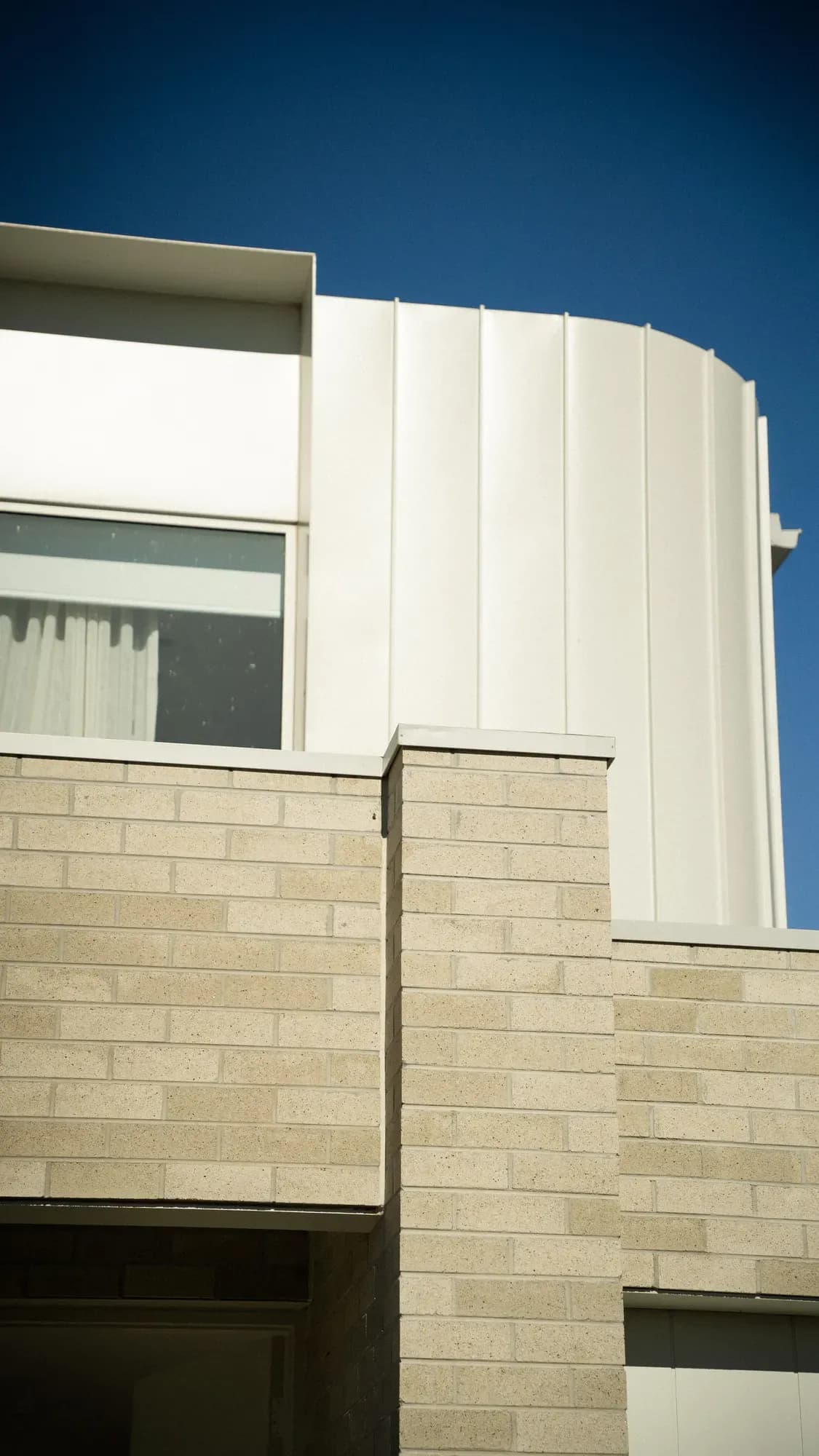 A pale brick and white-render townhouse against a deep blue sky