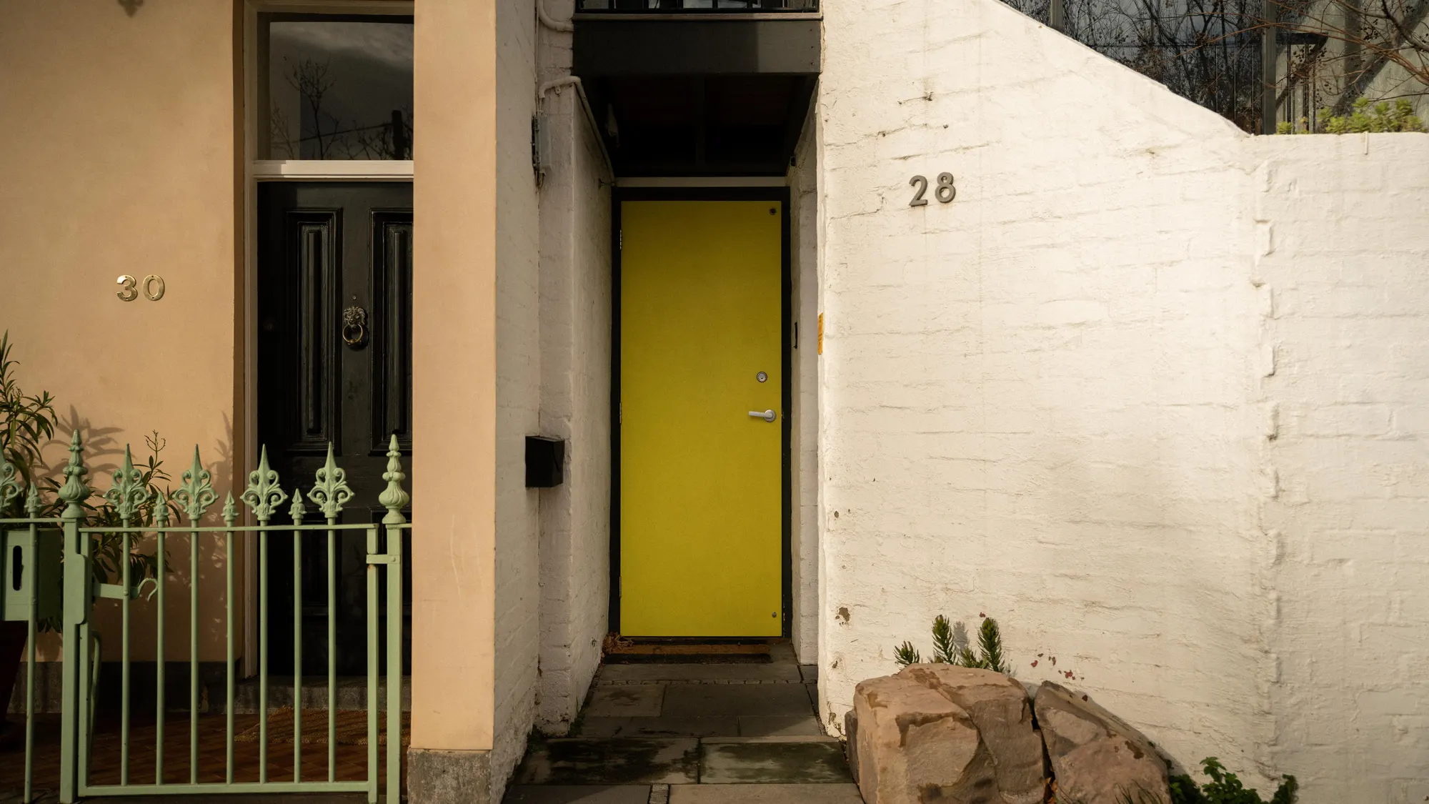 A yellow front door in a white-painted brick wall