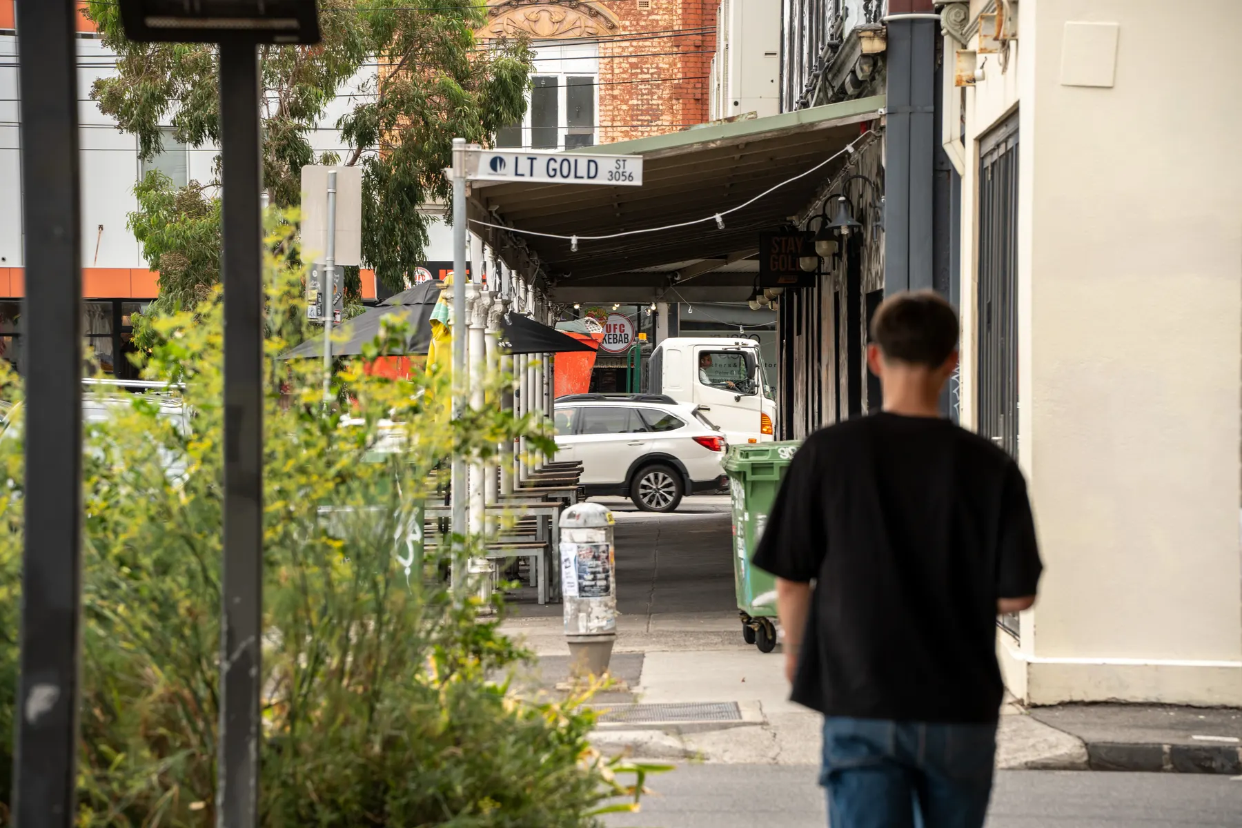 A man walking past shopfronts on a Brunswick street
