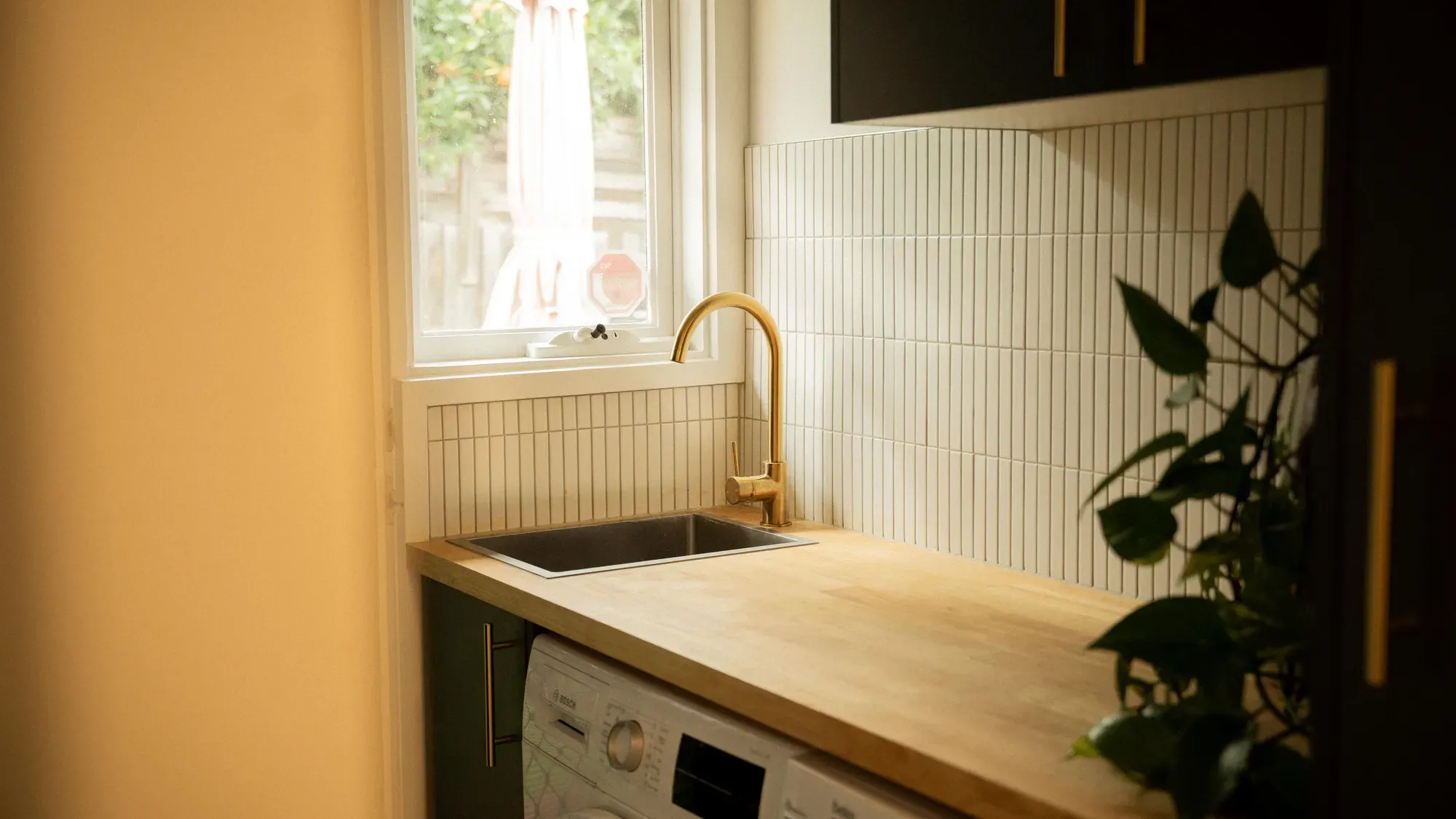 A brass tap over the sink against a white tiled splashback