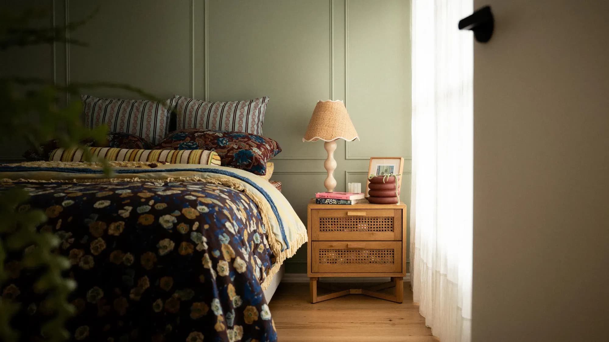 A bedroom in floral bedding, a rattan table beside it