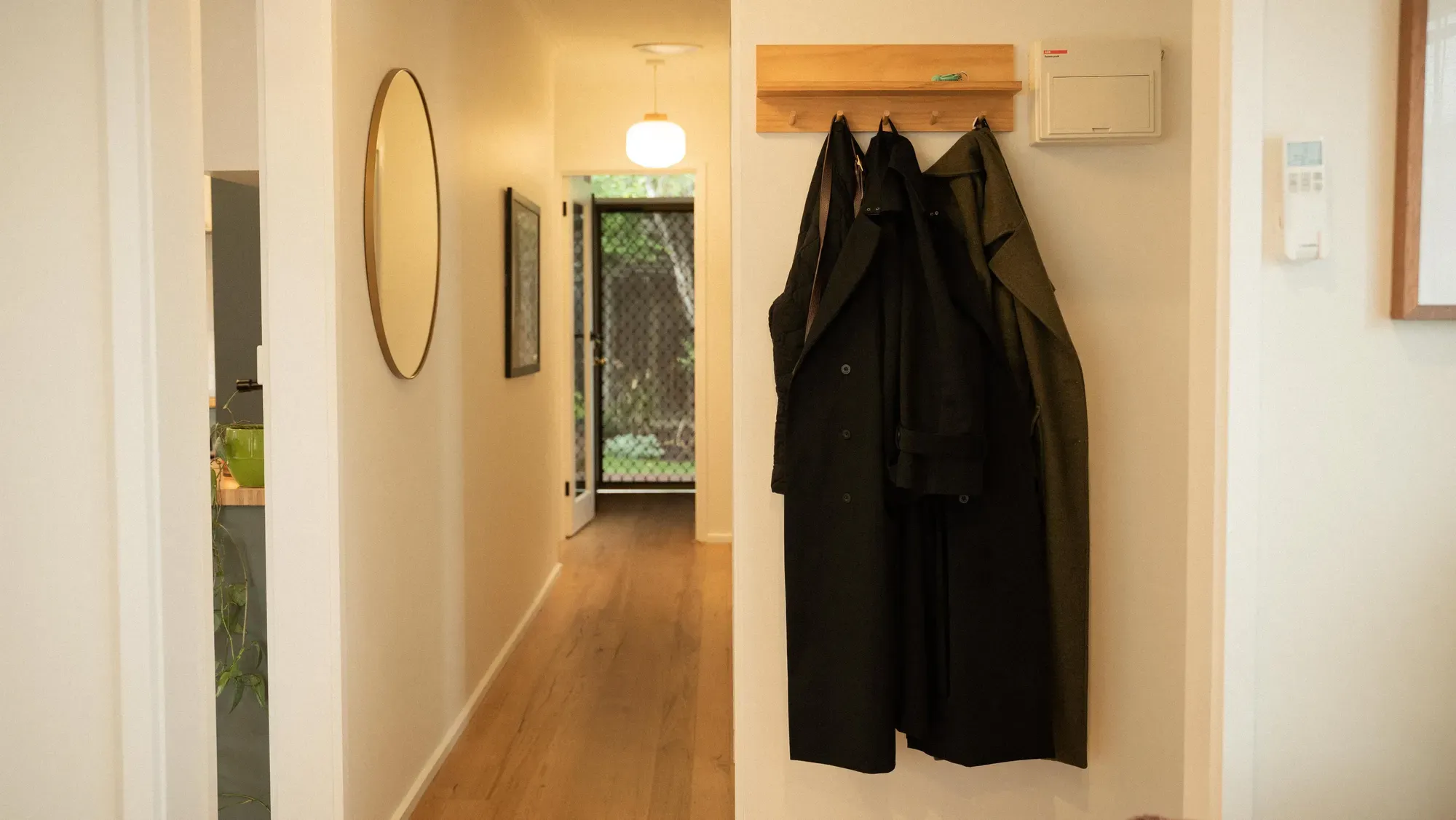 The hallway, coats on a rail beside a round mirror