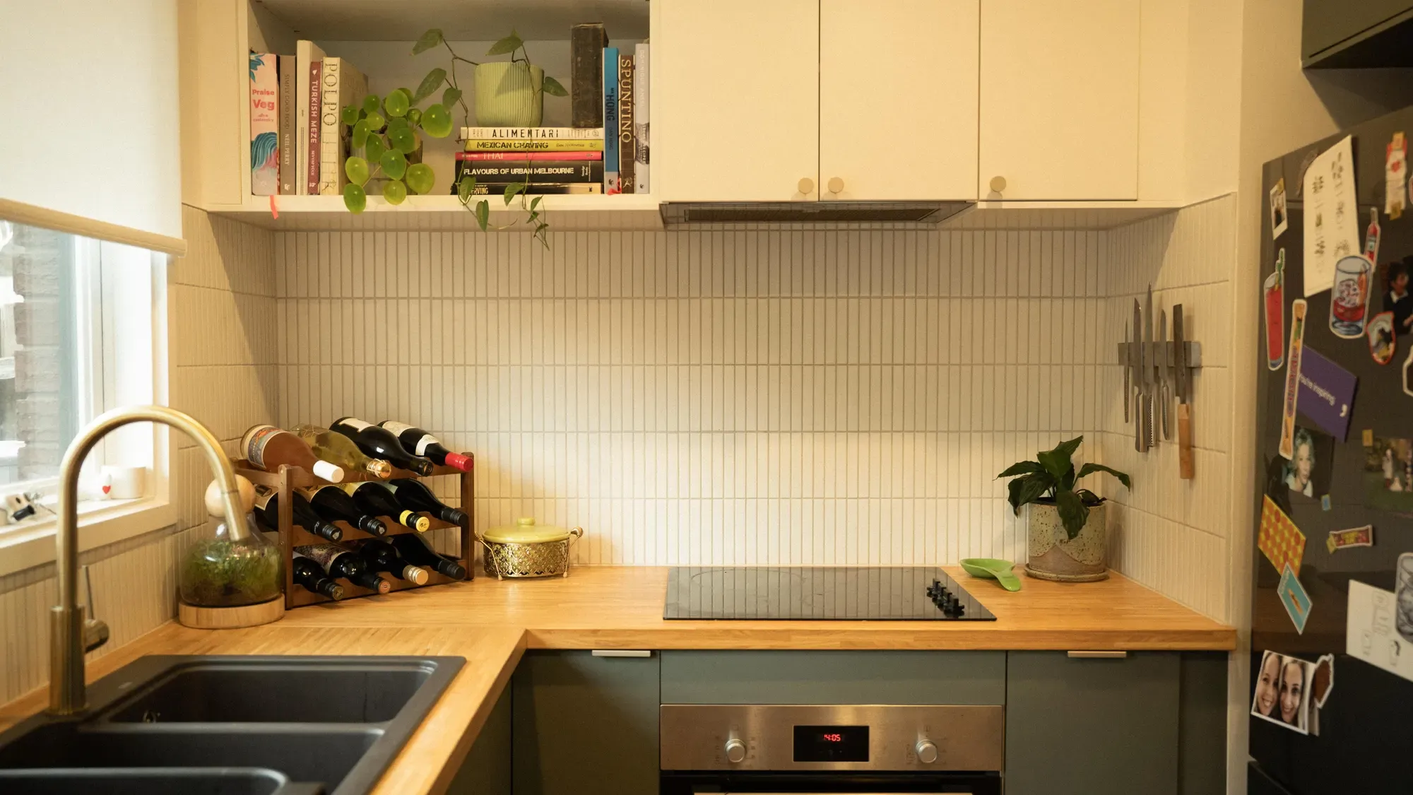The kitchen in green cabinetry with a timber bench
