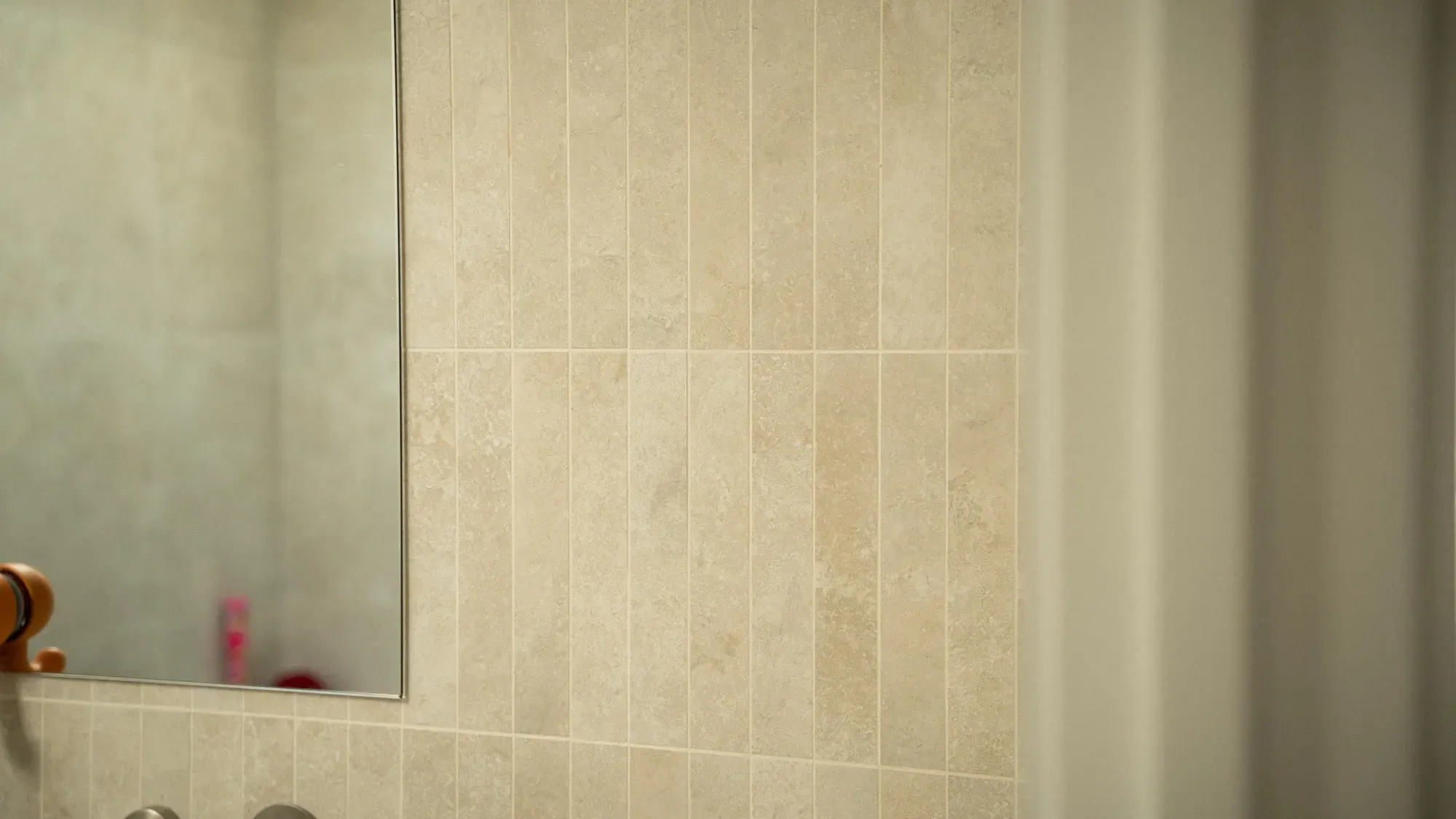 A tiled bathroom wall in warm light