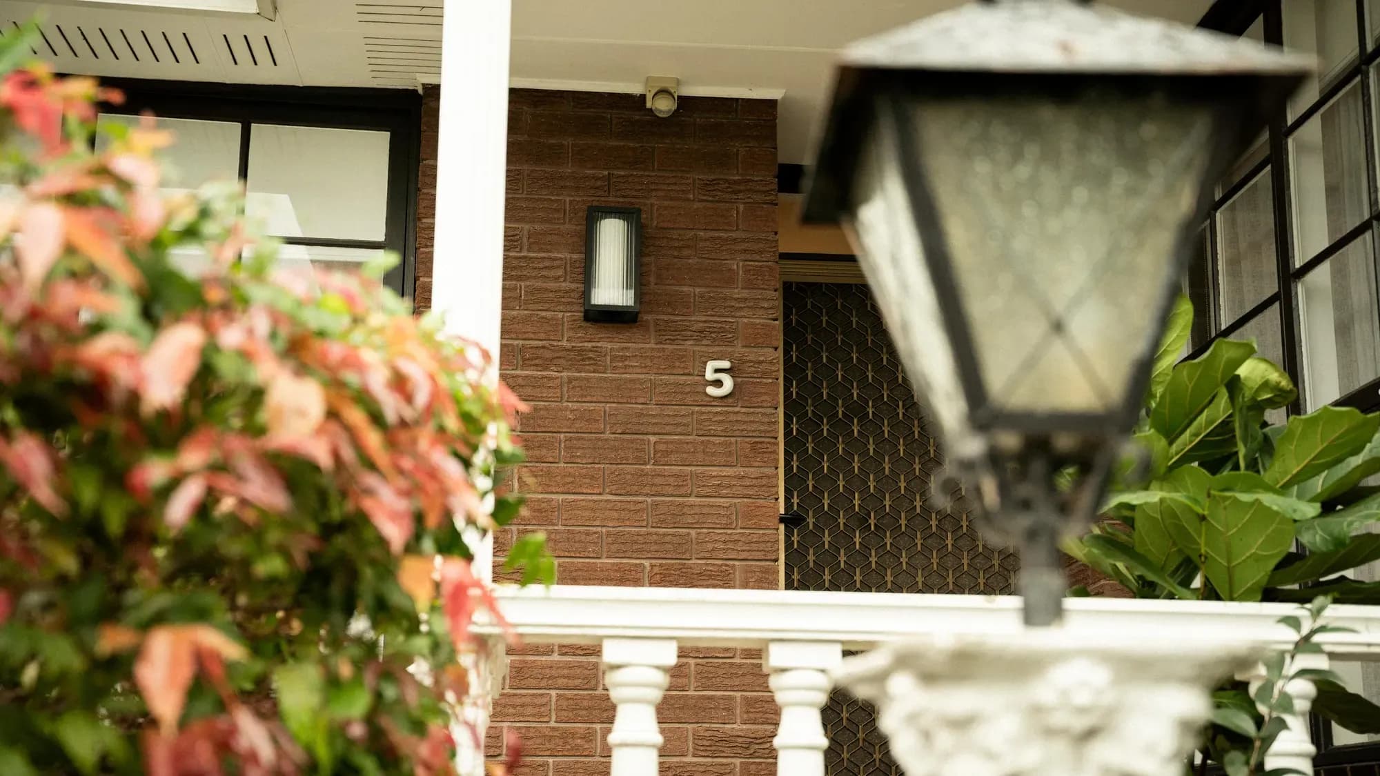The entry, a carriage lamp and red foliage beside it